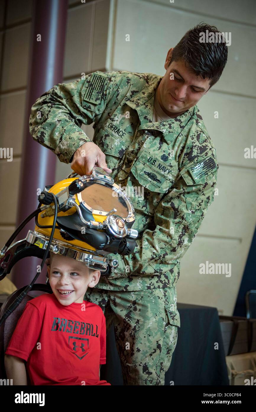 6 août 2018 - Milwaukee, Wisconsin, États-Unis - Navy Diver 1st Class Thomas Gerace, affecté au Groupe d'élimination des engins explosifs (EODGRU) 2, place un casque de plongée KM-37 sur un volontaire au Milwaukee public Museum pendant la semaine de la marine de Milwaukee. Le Navy Office of Community Outreach utilise le programme Navy week pour apporter des marins, de l'équipement et des écrans de la Navy à environ 14 villes américaines chaque année pour un programme d'une semaine d'engagements de sensibilisation conçus pour que les Américains puissent découvrir de première main comment la marine américaine est la marine dont la nation a besoin. (Crédit image : © U.S. Navy/ZUMA Wire/ZUMAPRESS.com) Banque D'Images