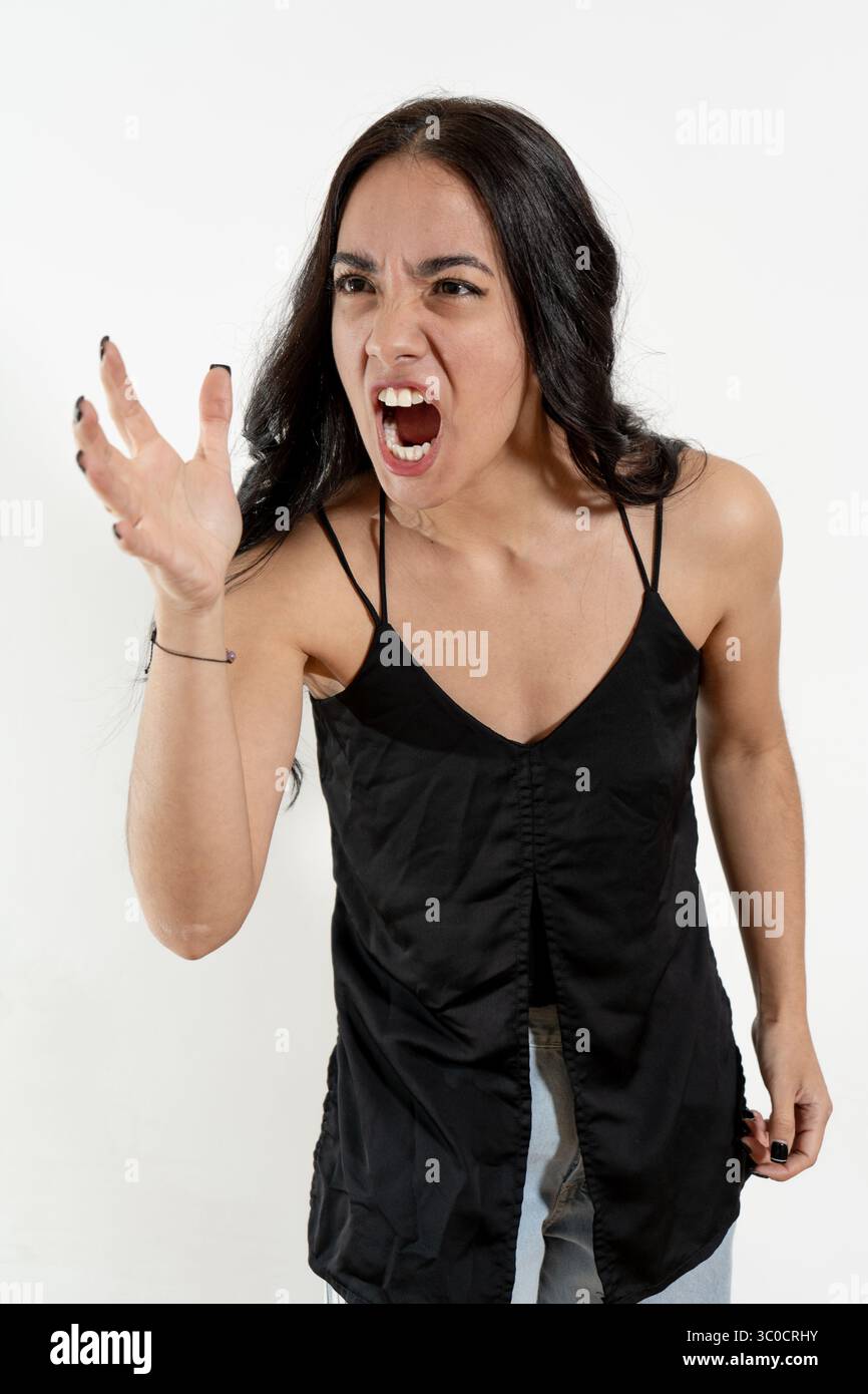 Femme hispanique en colère criant et faisant des gestes sur fond blanc Banque D'Images