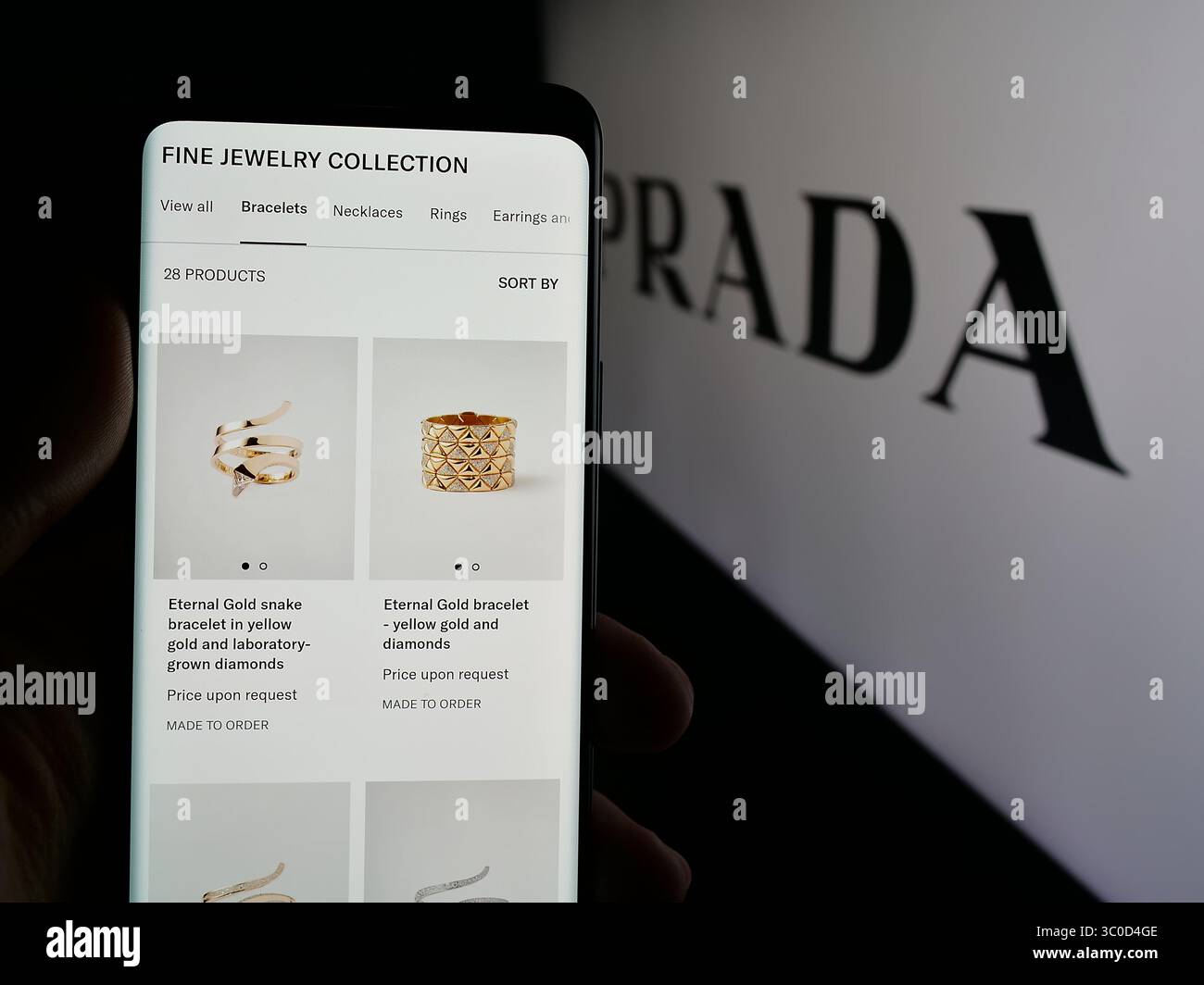Stuttgart, Allemagne - 2025 : personne tenant un smartphone avec la page web de la maison de couture de luxe Prada S.p.A. sur l'écran devant le logo. Banque D'Images