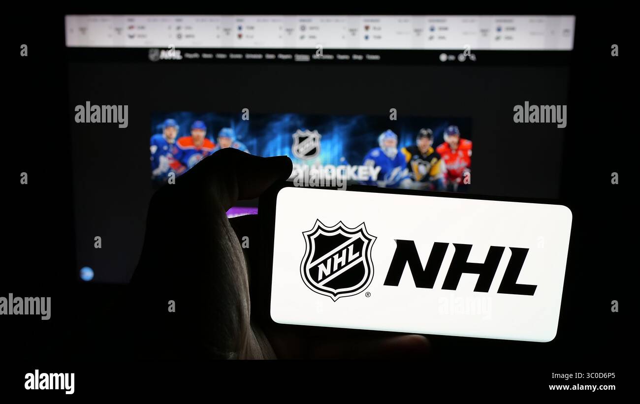 Stuttgart, Allemagne - 2025-05-05 : personne tenant un téléphone portable avec le logo de la Ligue nationale de hockey (LNH) sur l'écran devant la page Web. Banque D'Images