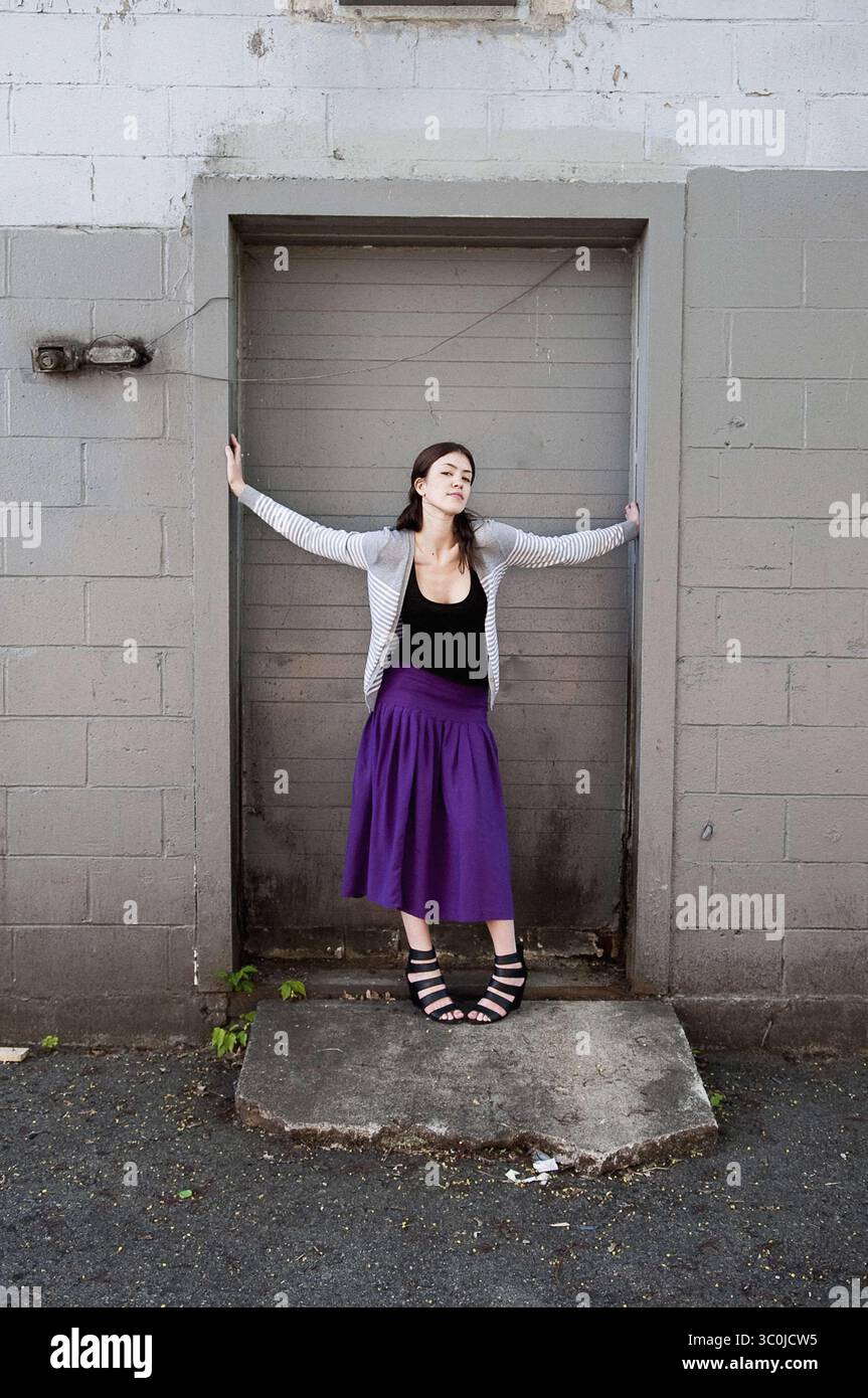 24 avril 2010 - New York, New York, États-Unis - jeune femme en jupe violette et pull gris posant contre la porte, bras tendus (crédit image : © Novo images/Glasshouse via ZUMA Wire) Banque D'Images