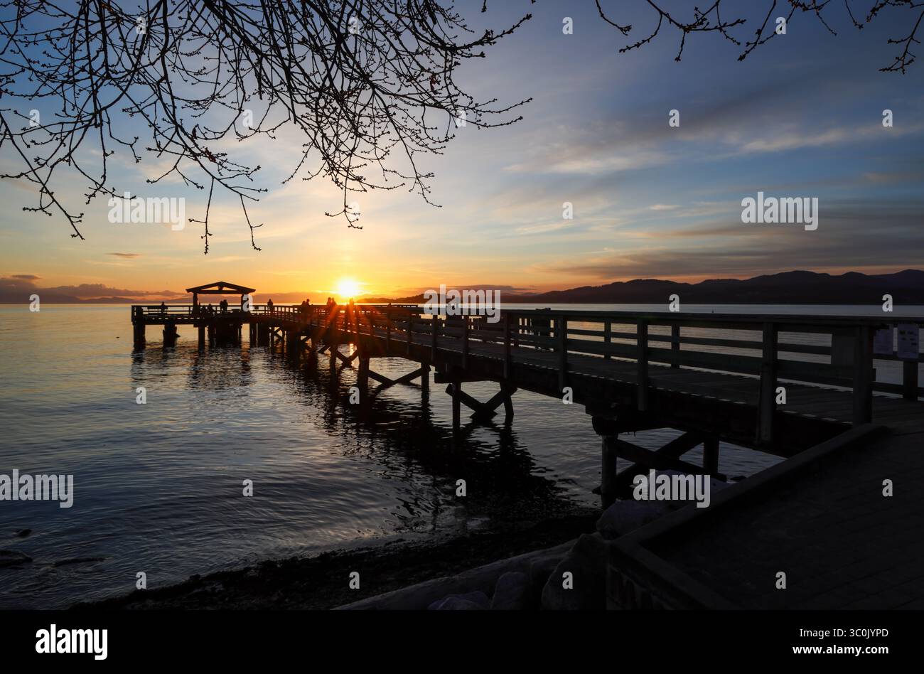Coucher de soleil derrière une jetée en bois silhouette, avec des reflets et des ondulations sur l'eau, Davis Bay, Sunshine Coast Highway, Sechelt Banque D'Images