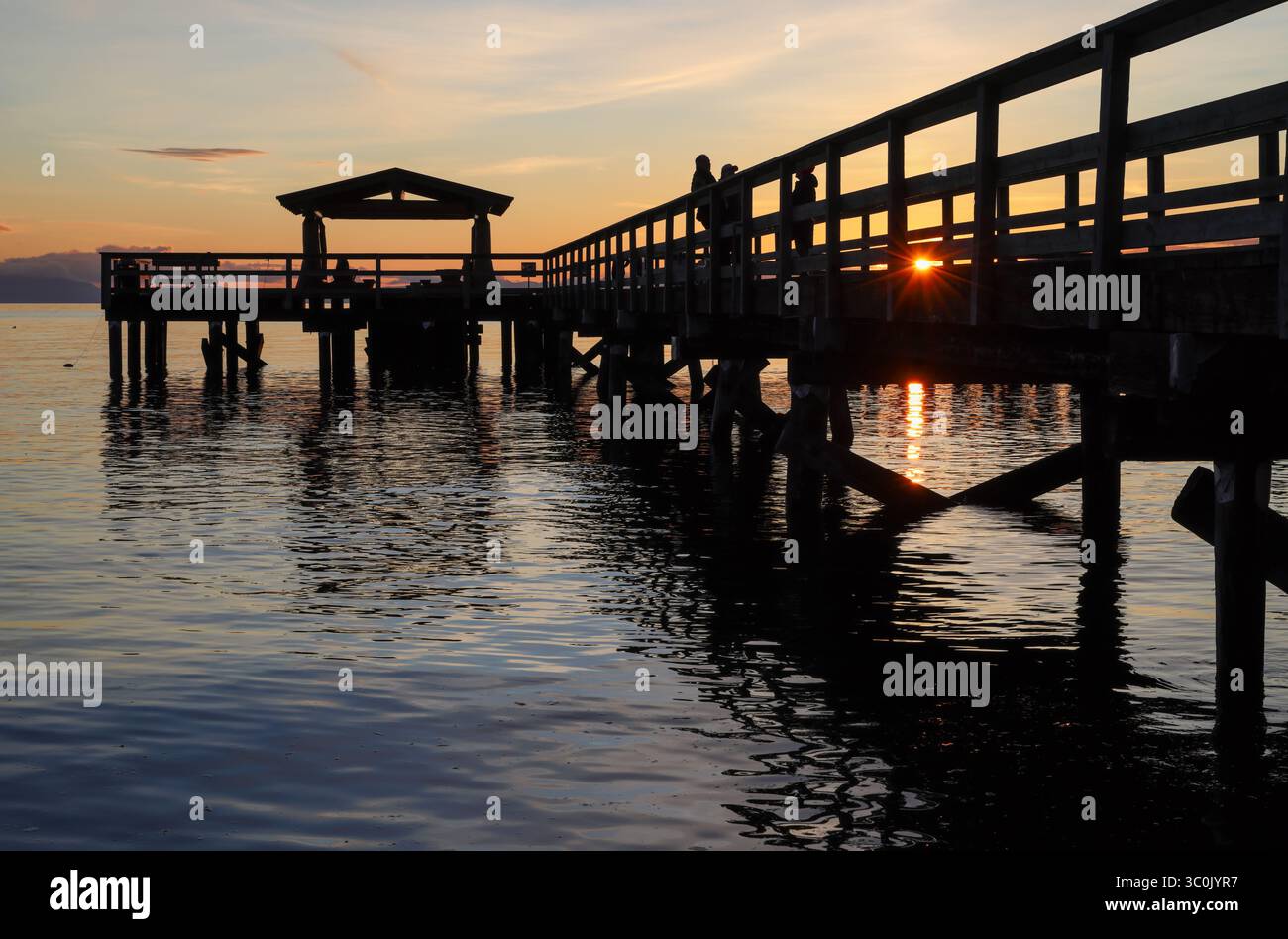 Coucher de soleil derrière une jetée en bois silhouette, avec des reflets et des ondulations sur l'eau, Davis Bay, Sunshine Coast Highway, Sechelt Banque D'Images