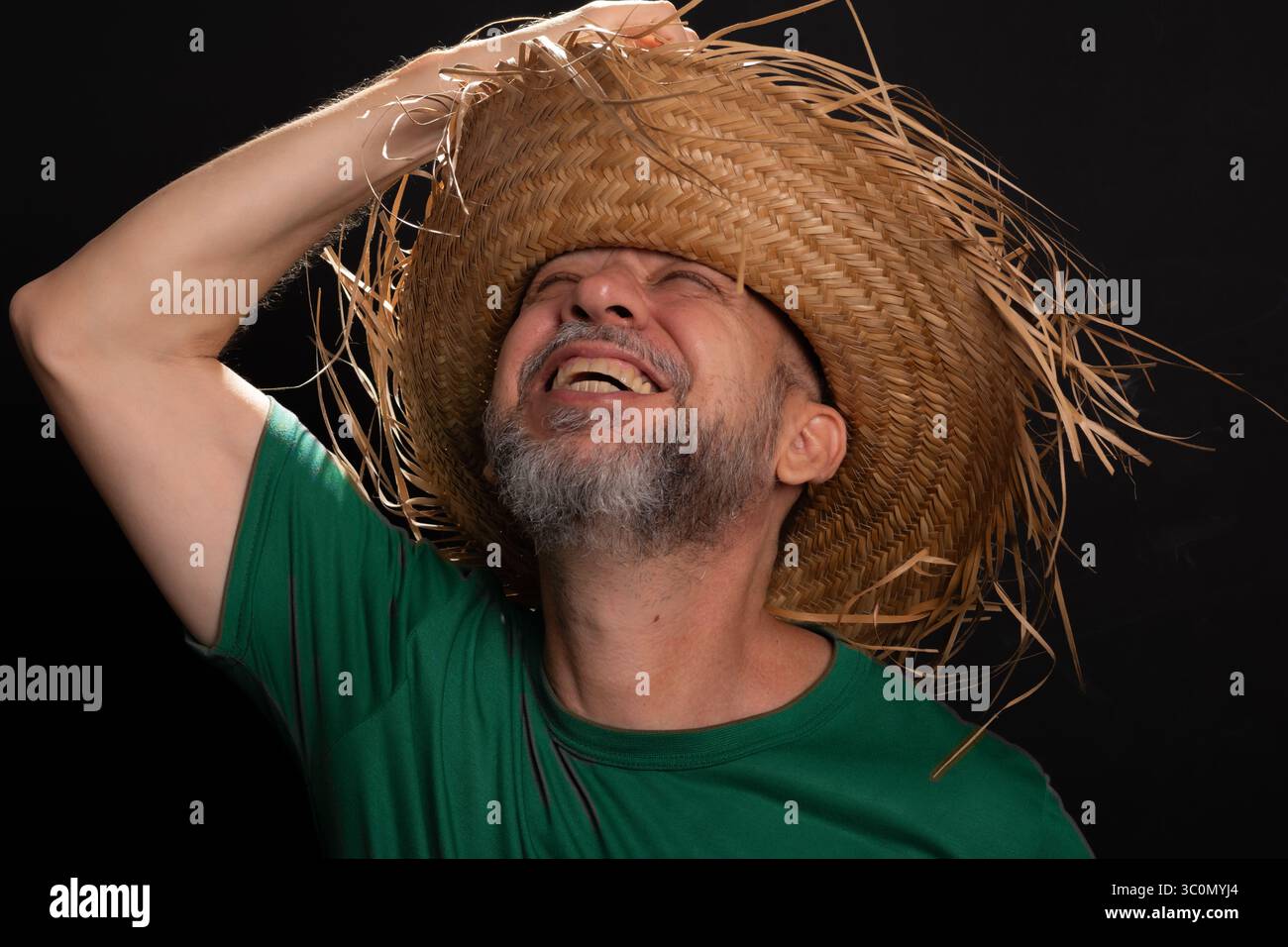 Homme barbu souriant en chapeau de paille et chemise verte habillé pour le festival Sao Joao au Brésil. Pays partie Banque D'Images