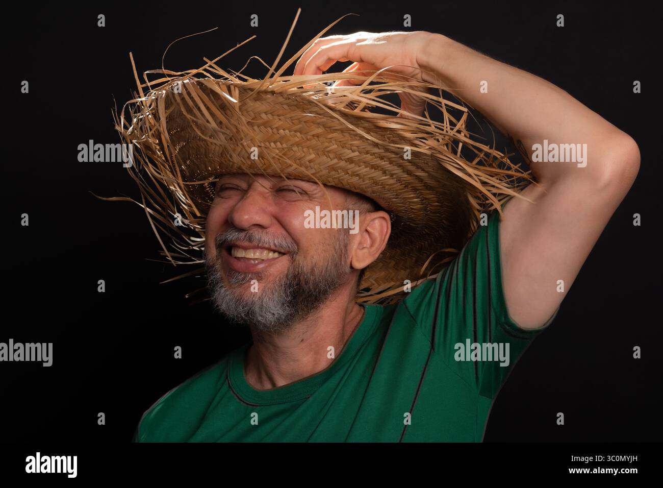 Homme barbu souriant en chapeau de paille et chemise verte habillé pour le festival Sao Joao au Brésil. Pays partie Banque D'Images
