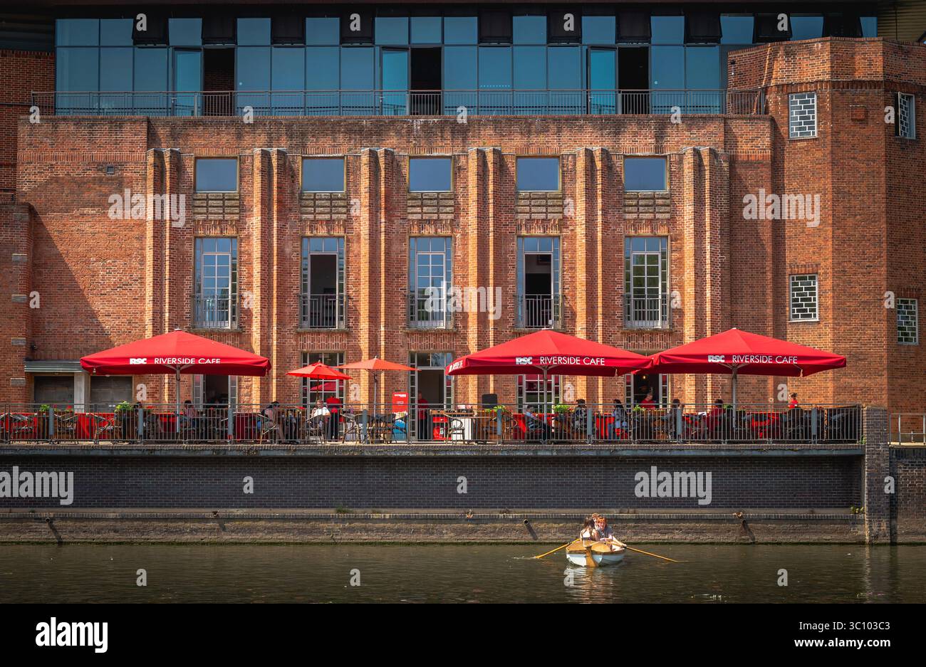 Une vue du Royal Shakespeare Theatre à Stratford upon Avon montrant le Riverside Café et un bateau à rames sur la rivière Avon Banque D'Images