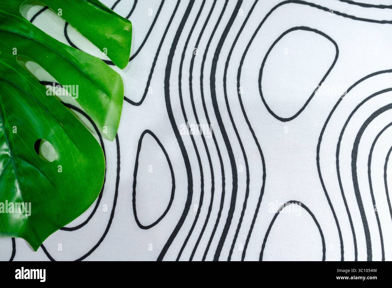 Surface de tissu avec des lignes de contour noires abstraites et des feuilles vertes tropicales. Parfait pour l'arrière-plan, les maquettes ou la conception visuelle moderne avec la nature. Banque D'Images