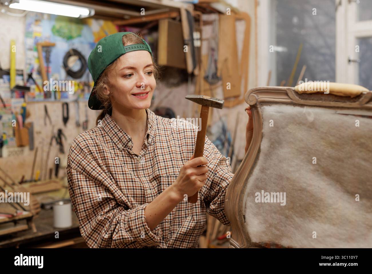 femme restaure vieille chaise en bois, travaille avec un marteau, concept de réparation et de restauration de vieux meubles. Copier l'espace Banque D'Images