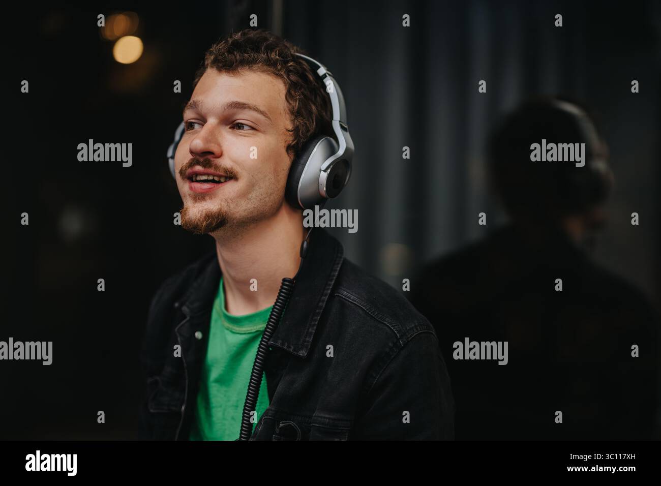Jeune homme appréciant la musique avec des écouteurs dans une atmosphère détendue Banque D'Images