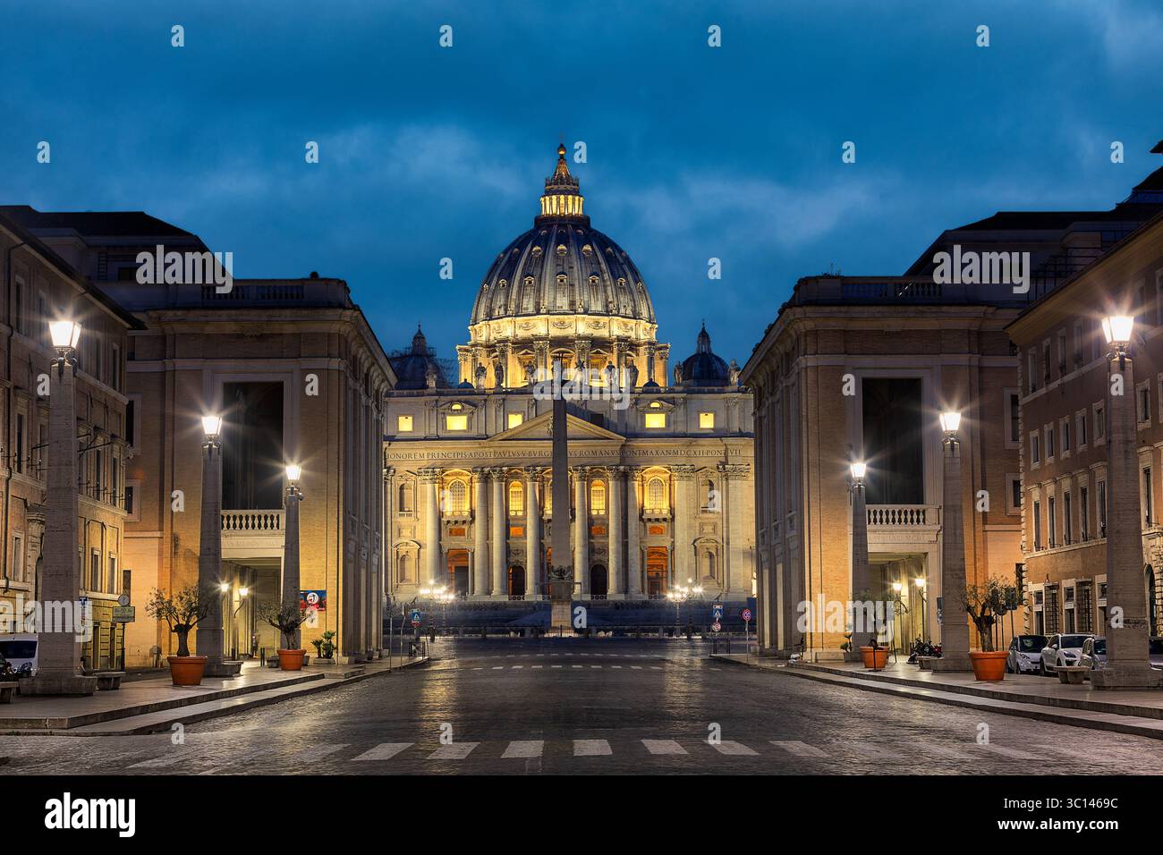 Vue de, basilique Pierre illuminée contre le ciel crépusculaire s'estompant, encadrée par des bâtiments symétriques et des lampadaires, Rome, Latium, Italie. Banque D'Images