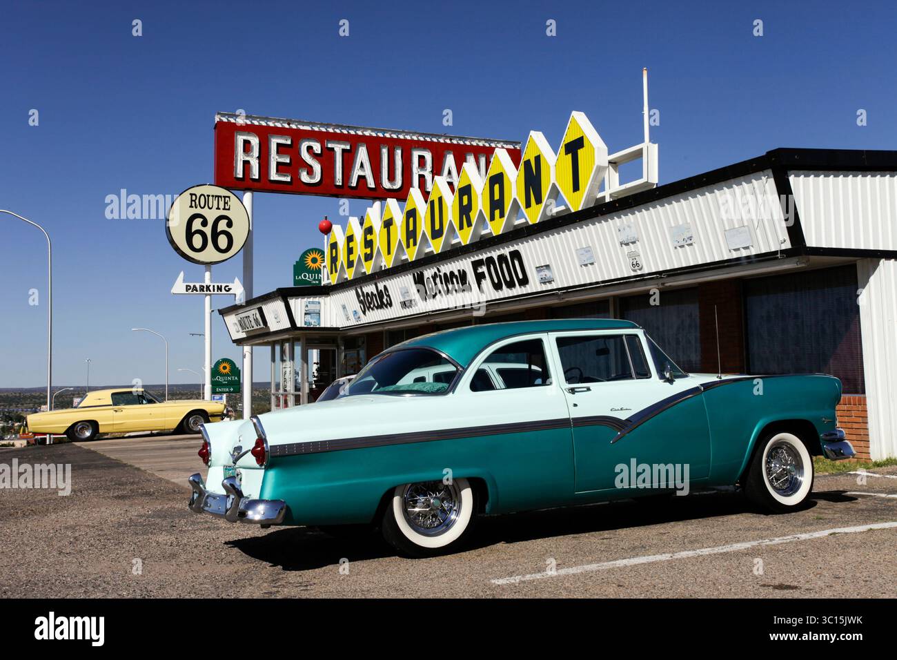 Santa Rosa, Nouveau-Mexique, États-Unis. Restaurant drive-up du milieu du siècle avec une voiture bleue des années 1950 et un panneau route 66 sous un ciel ensoleillé Banque D'Images