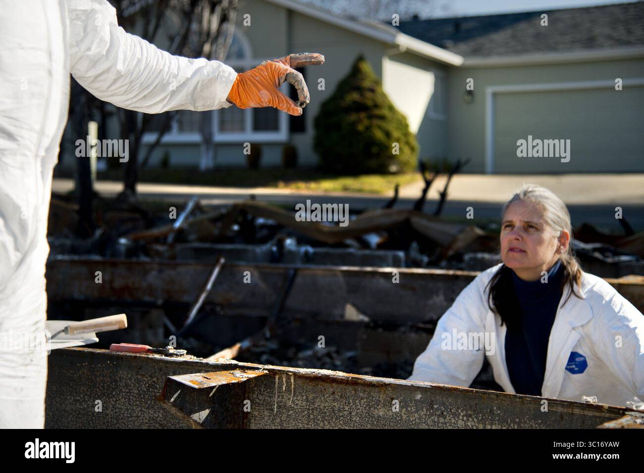 12 janvier 2019 - Paradise, CA, États-Unis - les archéologues bénévoles Mike Newland montrent un indice à Anmarie Media alors qu'ils cherchent des crémains dans des maisons brûlées dans le Camp Fire à Paradise le 12 janvier 2019. En utilisant l'aide d'un chien entraîné à sentir les restes humains, les indices de la famille et l'analyse de la couleur et de la texture, les crémains peuvent être distingués parmi les cendres de la propriété des gens. Les cremains sont ensuite donnés à la famille afin qu'ils ne soient pas envoyés dans une décharge de déchets toxiques. Le groupe espère que leur travail sera reconnu par la FEMA comme un service important à offrir aux victimes du feu pour eux Banque D'Images