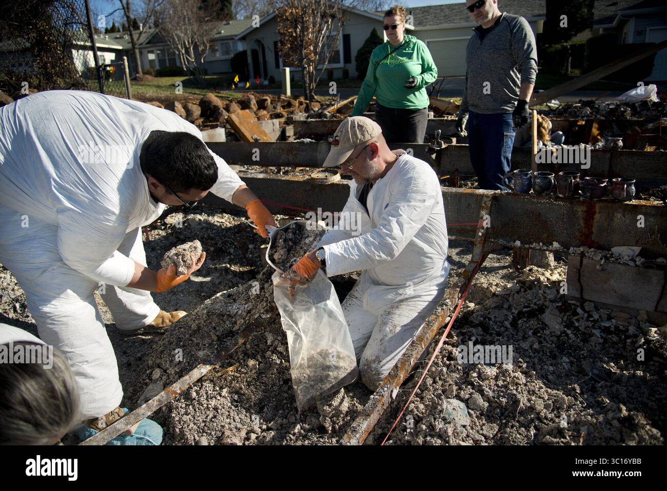 12 janvier 2019 - Paradise, CA, États-Unis - archéologues bénévoles, de gauche à droite, Chris Sapolu et Mike Newland recueillent des crémains dans des maisons brûlées dans le feu de camp à Paradise le 12 janvier 2019. Derrière eux se trouvent Chrissie Weston et son mari Steve. Ce sont les restes du grand-parent de Chrissie. En utilisant l'aide d'un chien entraîné à sentir les restes humains, les indices de la famille et l'analyse de la couleur et de la texture, les crémains peuvent être distingués parmi les cendres de la propriété des gens. Les cremains sont ensuite donnés à la famille afin qu'ils ne soient pas envoyés dans une décharge de déchets toxiques. Le groupe l'espère Banque D'Images