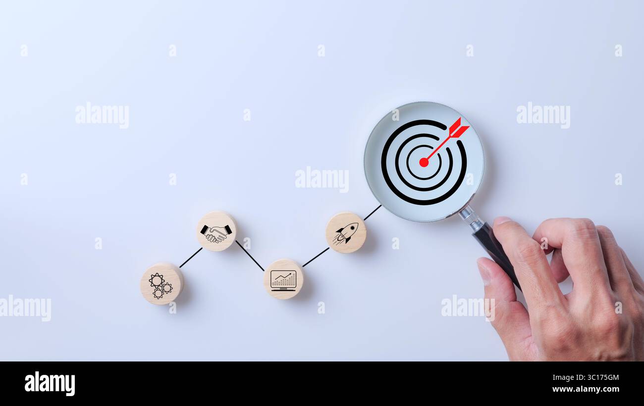 Concept d'objectif d'entreprise. Main tenant la loupe pour focaliser sur l'icône cible. Étape dans la planification du développement pour le succès, stratégie marketing, Digital Tech Banque D'Images