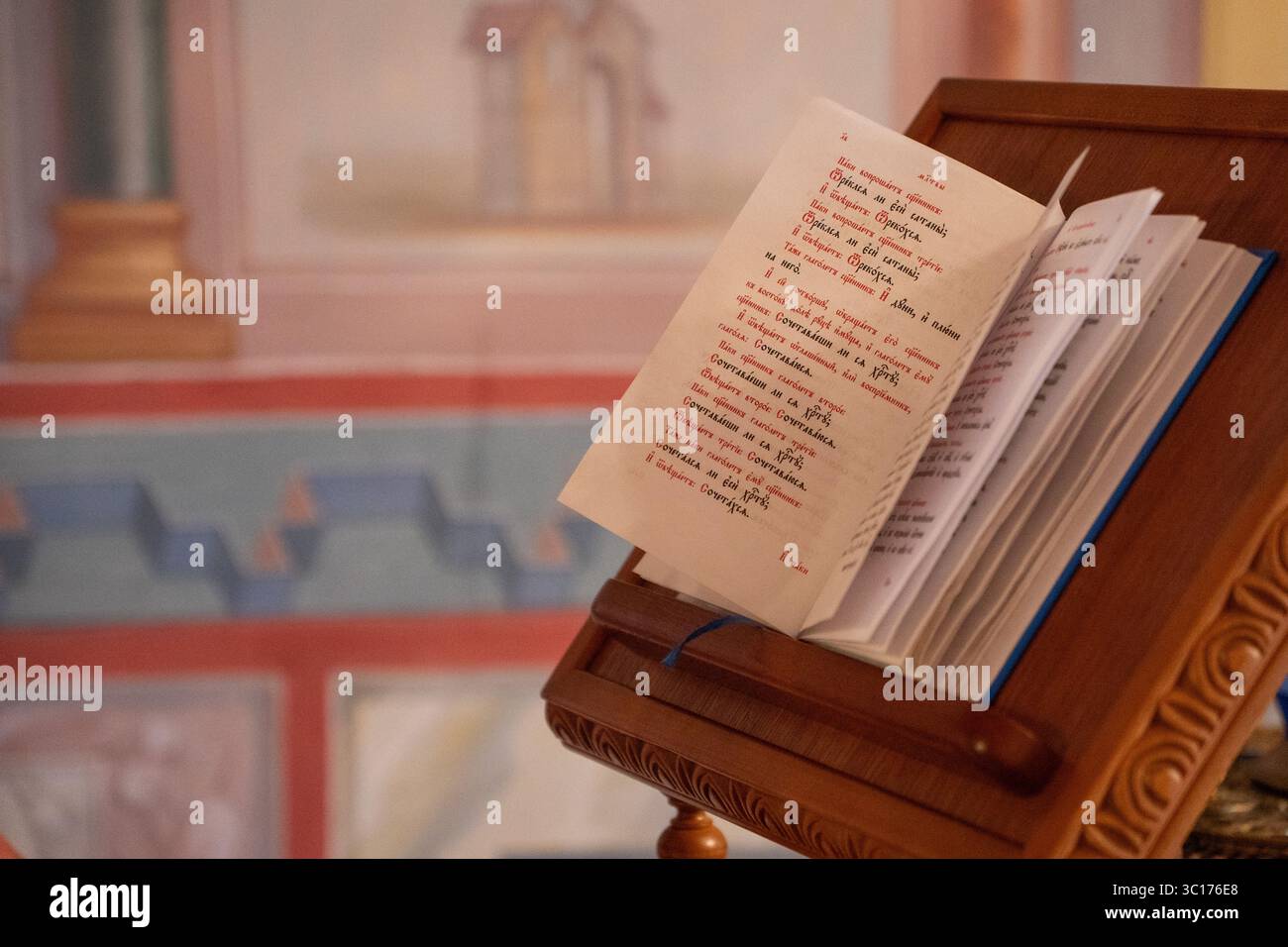 Zvenigorod, Russie - 12 juillet 2025 : Livre liturgique orthodoxe ouvert affiché sur un stand en bois avec des pages décoratives en texte rouge et noir Banque D'Images