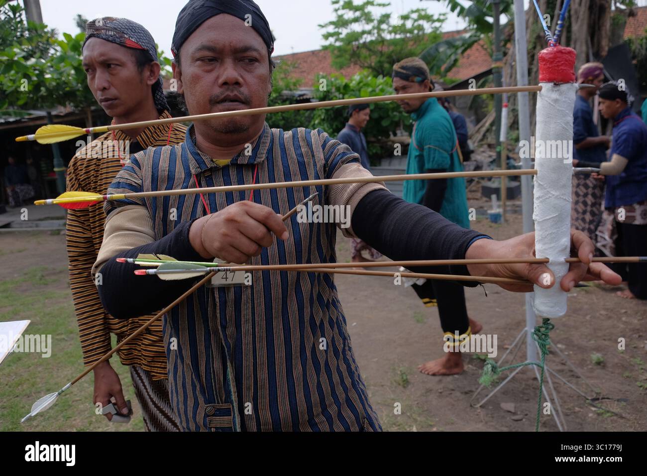 Un homme sort une flèche coincée à la surface d'une cible lors d'un sport de tir à l'arc javanais traditionnel, le Jemparingan. Banque D'Images