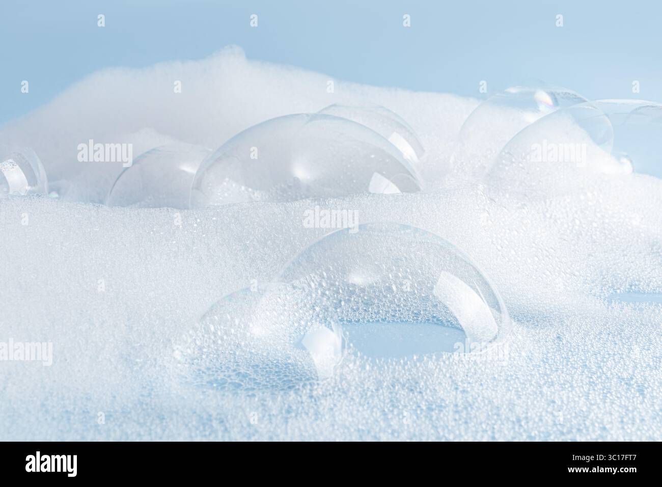 Grande bulle de savon transparente sur la surface de mousse des cosmétiques détergents, shampooing, savon, poudre sur fond bleu. Vue de face. Gros plan des bulles Banque D'Images