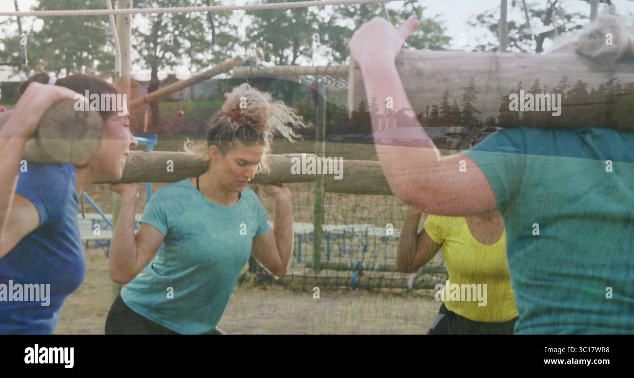 Portant des bûches en bois lourdes femmes portant des vêtements de sport marchant à travers la course d'obstacles de parc boueux, filets Banque D'Images