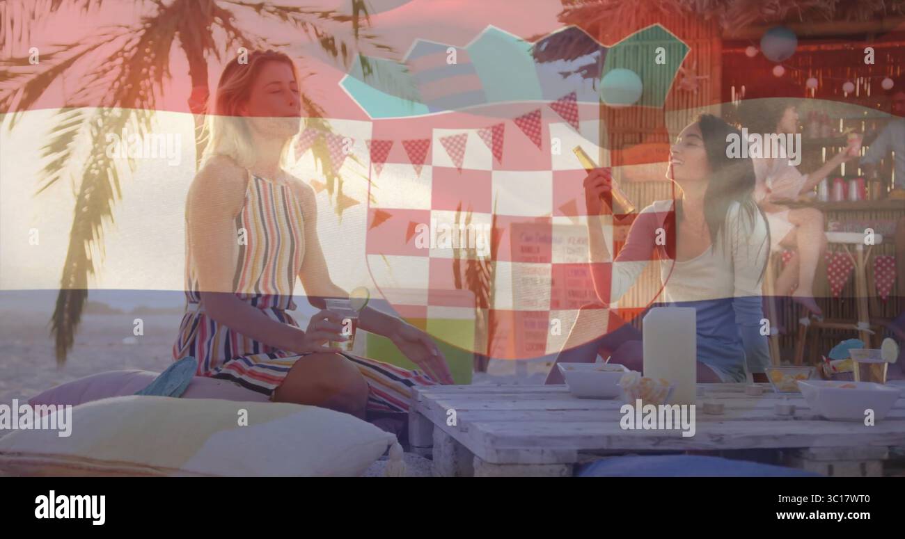 Femme relaxante dans la robe de soleil rayée assis et tenant un cocktail au salon de plage, avec table de palette Banque D'Images