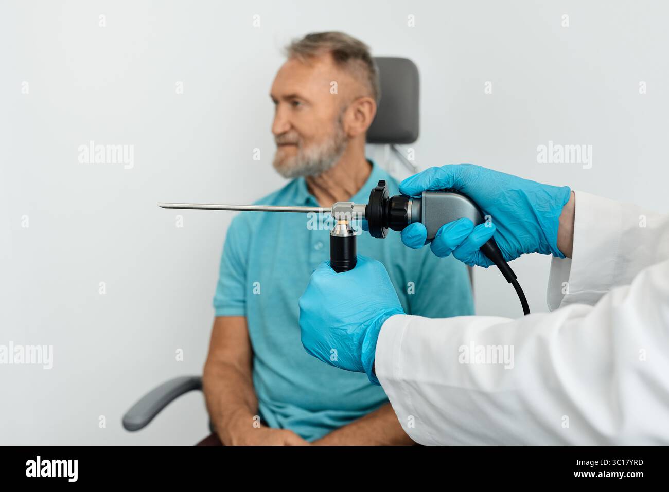 Médecin avec endoscope pour vidéo endoscopique dans les mains pour vérifier les organes ORL pendant la procédure d'examen d'un homme âgé assis dans la chaise ORL Banque D'Images