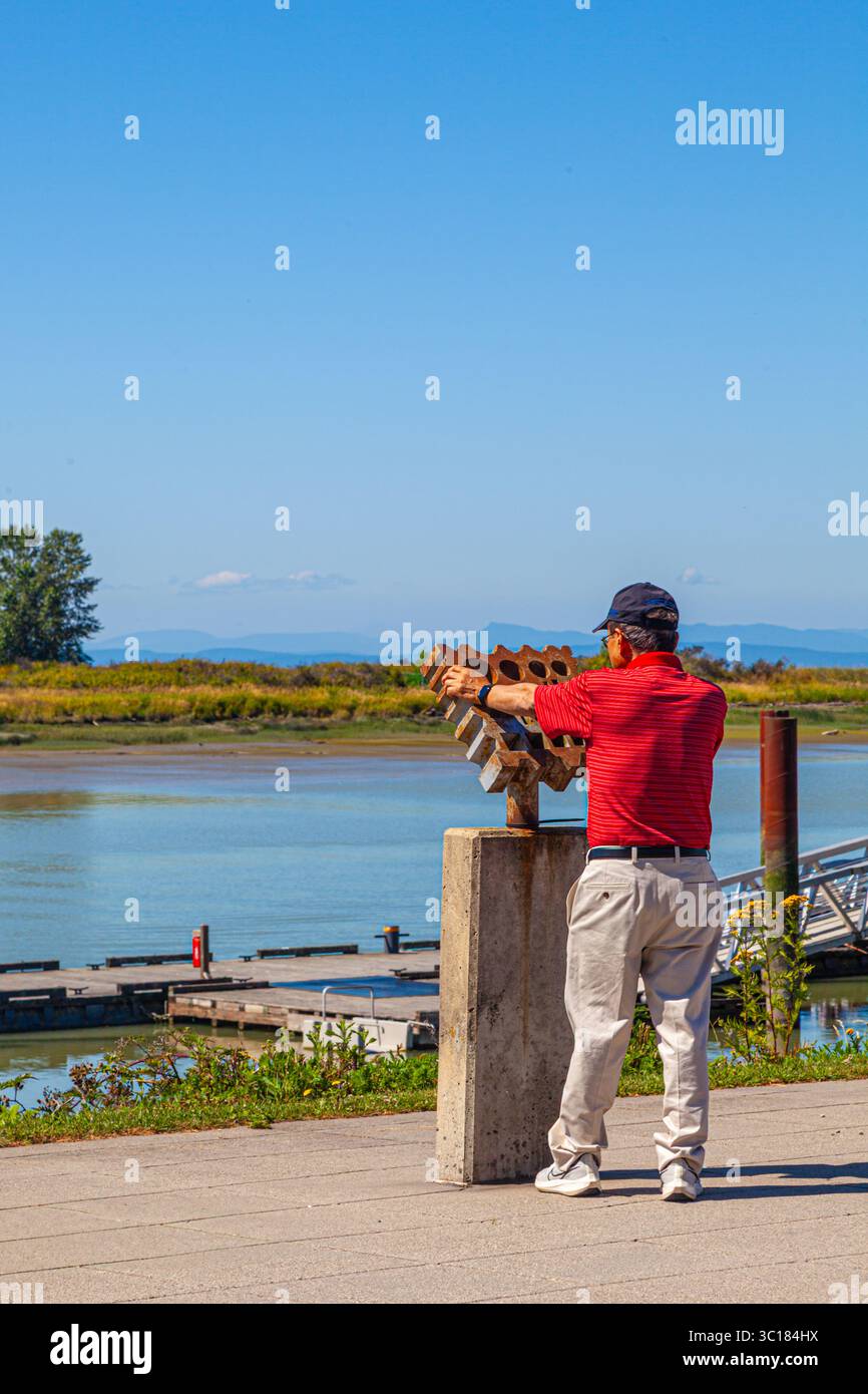 Homme qui étudie un artefact métallurgique le long du front de mer de Steveson en Colombie-Britannique au Canada Banque D'Images