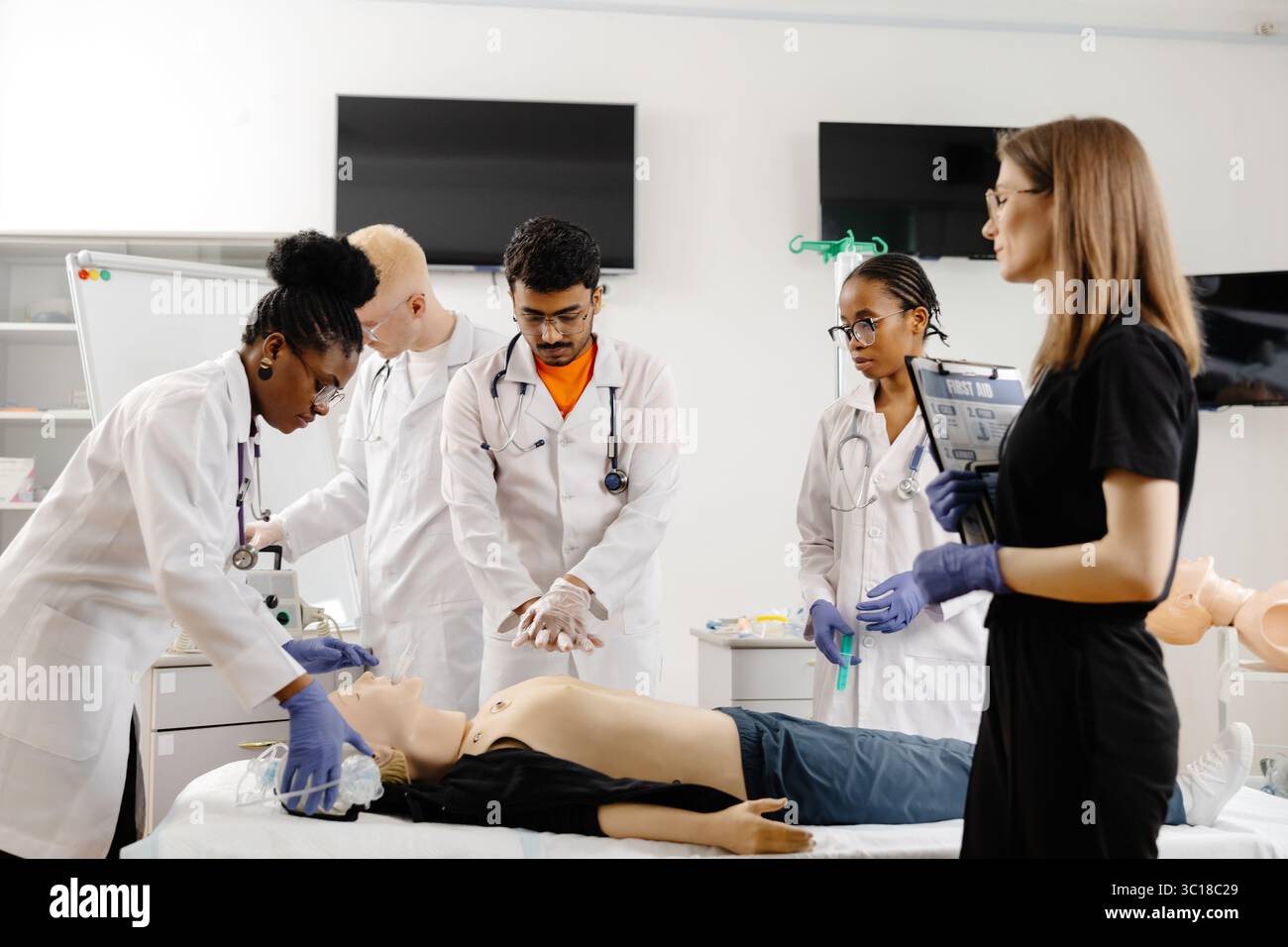 Groupe d'étudiants en médecine divers apprenant à effectuer une réanimation cardio-pulmonaire sur un mannequin de formation Banque D'Images