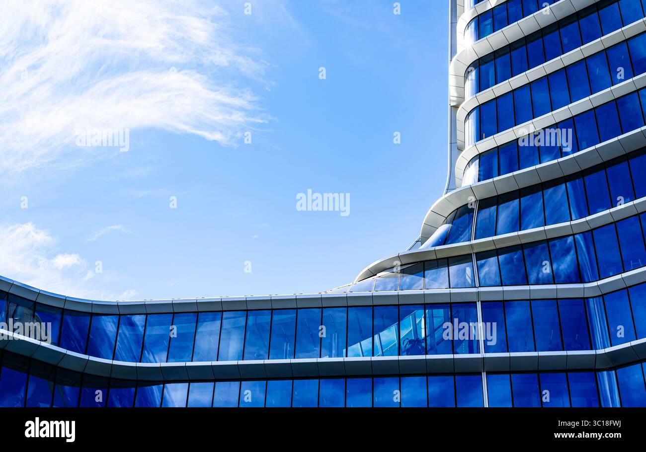 Immeuble résidentiel moderne à plusieurs étages avec façade vibrante, grands balcons et vue panoramique urbaine sous ciel bleu clair Banque D'Images