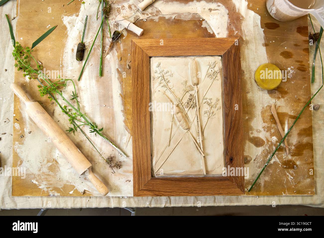 Relief en plâtre botanique fini dans un cadre en bois avec des empreintes de fleurs. Résultat d'illustration faite à la main DIY, décoration florale créative fabriquée étape par étape Banque D'Images