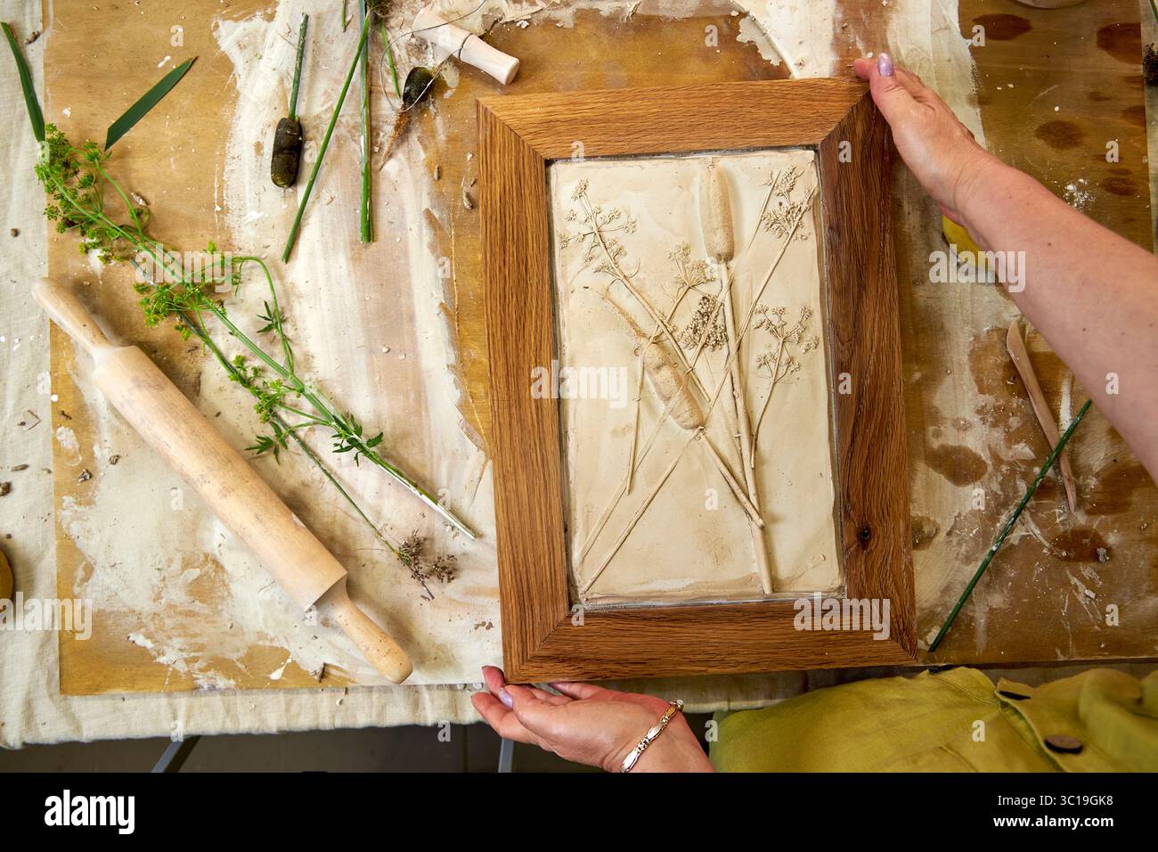 Relief en plâtre botanique fini dans un cadre en bois avec des empreintes de fleurs. Résultat d'illustration faite à la main DIY, décoration florale créative fabriquée étape par étape Banque D'Images