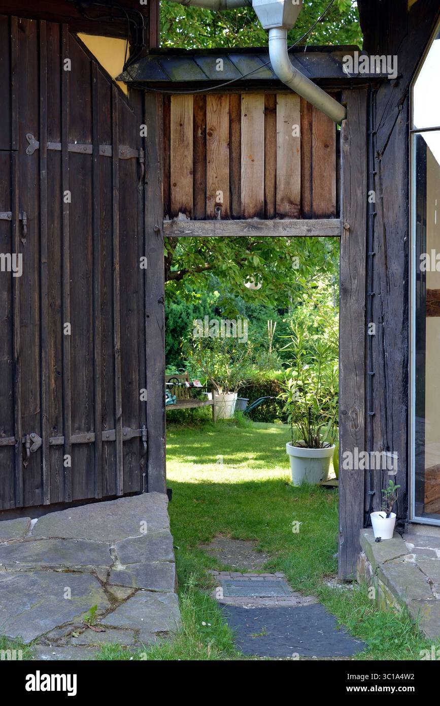 Ancienne porte en bois encadrant un jardin verdoyant, Allemagne Banque D'Images