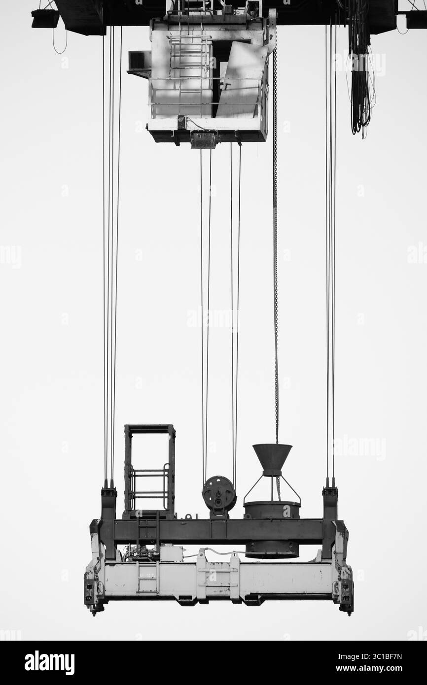 Cabine, câbles et crochets d'une grue à conteneurs, avec une porte cassée. En noir et blanc. Banque D'Images