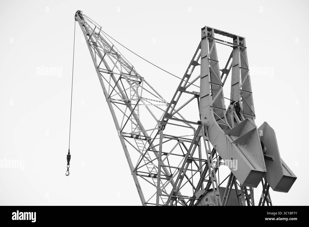 Grue portuaire, en noir et blanc, dans un port commercial en attente de sa prochaine expédition. Banque D'Images