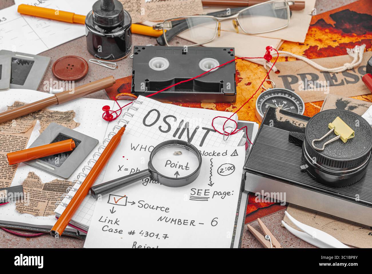 Espace de travail créatif sur le thème OSINT avec des outils vintage, des notes manuscrites et des éléments de presse sur une table grunge. Accessoires thématiques, pose à plat, gros plan Banque D'Images