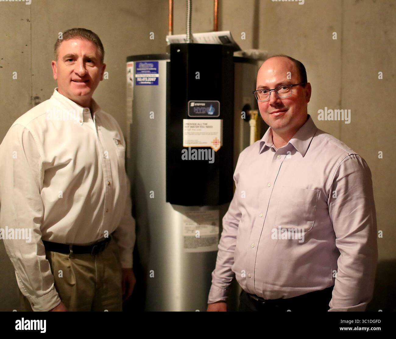 15 février 2018 - Lakeville, MN, États-Unis - Dave Reinke, de la Dakota Electric Association, et Jeff Haase, de Great River Energy, ont travaillé ensemble pour apporter une nouvelle technologie à une subdivision de Lakeville équipée de chauffe-eau intelligents qui ont réduit les coûts d'électricité de deux tiers. Ici, Dave Reinke, à gauche, et Jeff Haase sont photographiés à côté d'un chauffe-eau Steffe's Hydro plus, une unité de stockage thermique électrique alimentée par le réseau, qui se branche dans la technologie pour stocker l'énergie renouvelable. Et vu jeudi 15 février 2018, à Lakeville, MN....... La technologie permettra aux 81 nouvelles maisons d'un lotissement à Lakeville d'être Banque D'Images