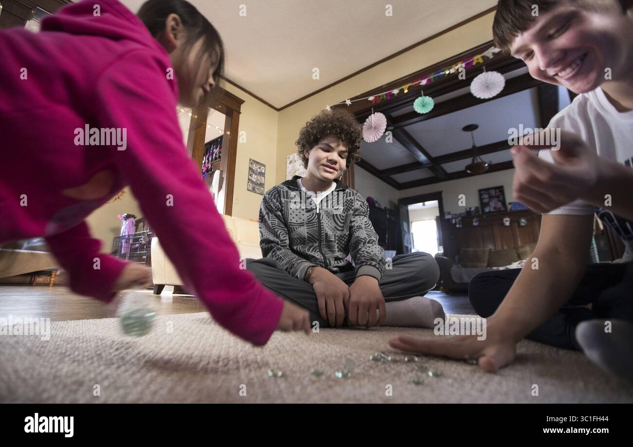 Mars 15, 2017 - créé Paul, MN, U.S.A - Minnehaha Academy Students Peter Shaffer, from right, 14 ans, et Daniel Rose, 14 ans, jouez à un jeu de marbre Hmong avec Diav vue, 7 ans, tout en restant chez sa mère à la maison Paul. ....RENSEIGNEMENTS GÉNÉRAUX : à St Paul le mercredi 15 mars 2017. City Stay est une occasion pour les élèves du secondaire du Minnesota de faire des séjours à la maison dans les maisons d'autres résidents locaux. Le programme d'échanges culturels favorise de nouvelles relations entre les communautés européennes, latino-américaines, somaliennes et hmong du Minnesota. (Crédit image : Leila Navidi/Minneapolis Star Tribune/TNS via ZUMA Wire) Banque D'Images