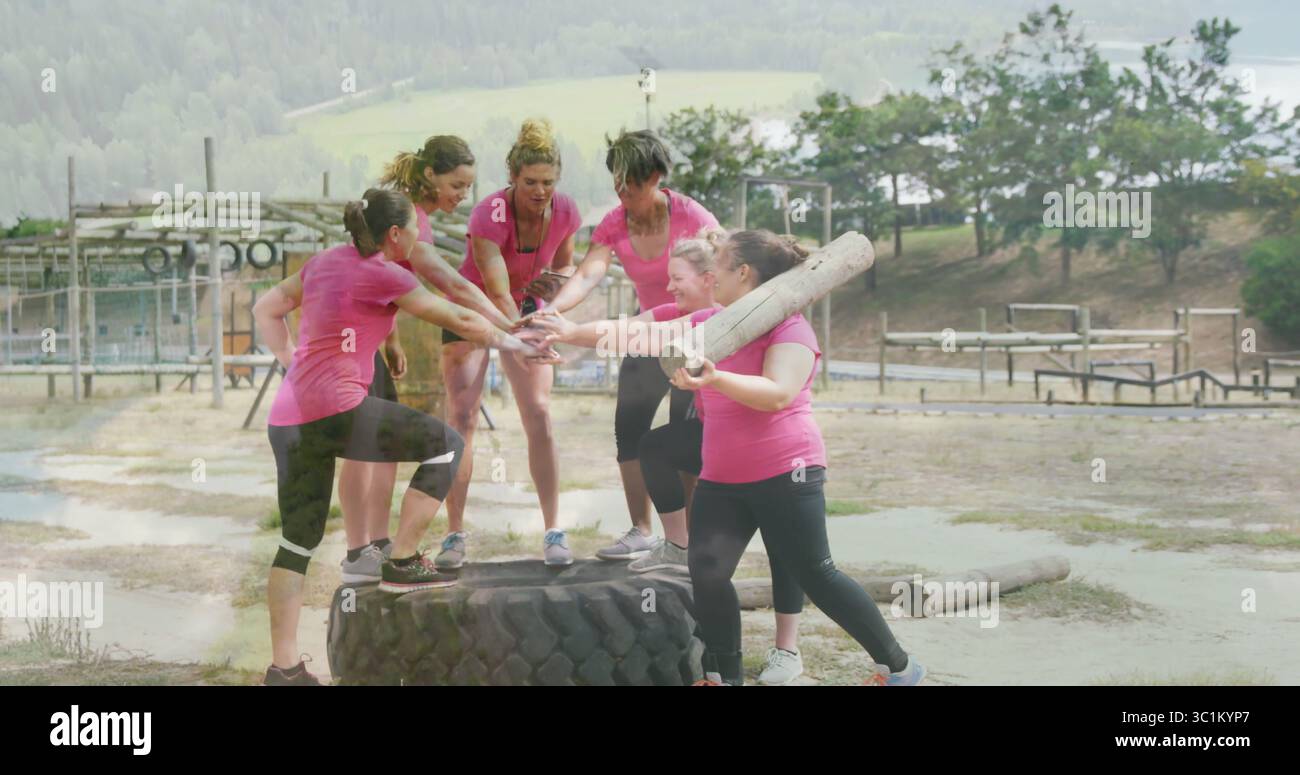 Groupe de femmes en sportswear rose se réunissant au parcours d'obstacles, avec pneu de tracteur et bûche en bois Banque D'Images