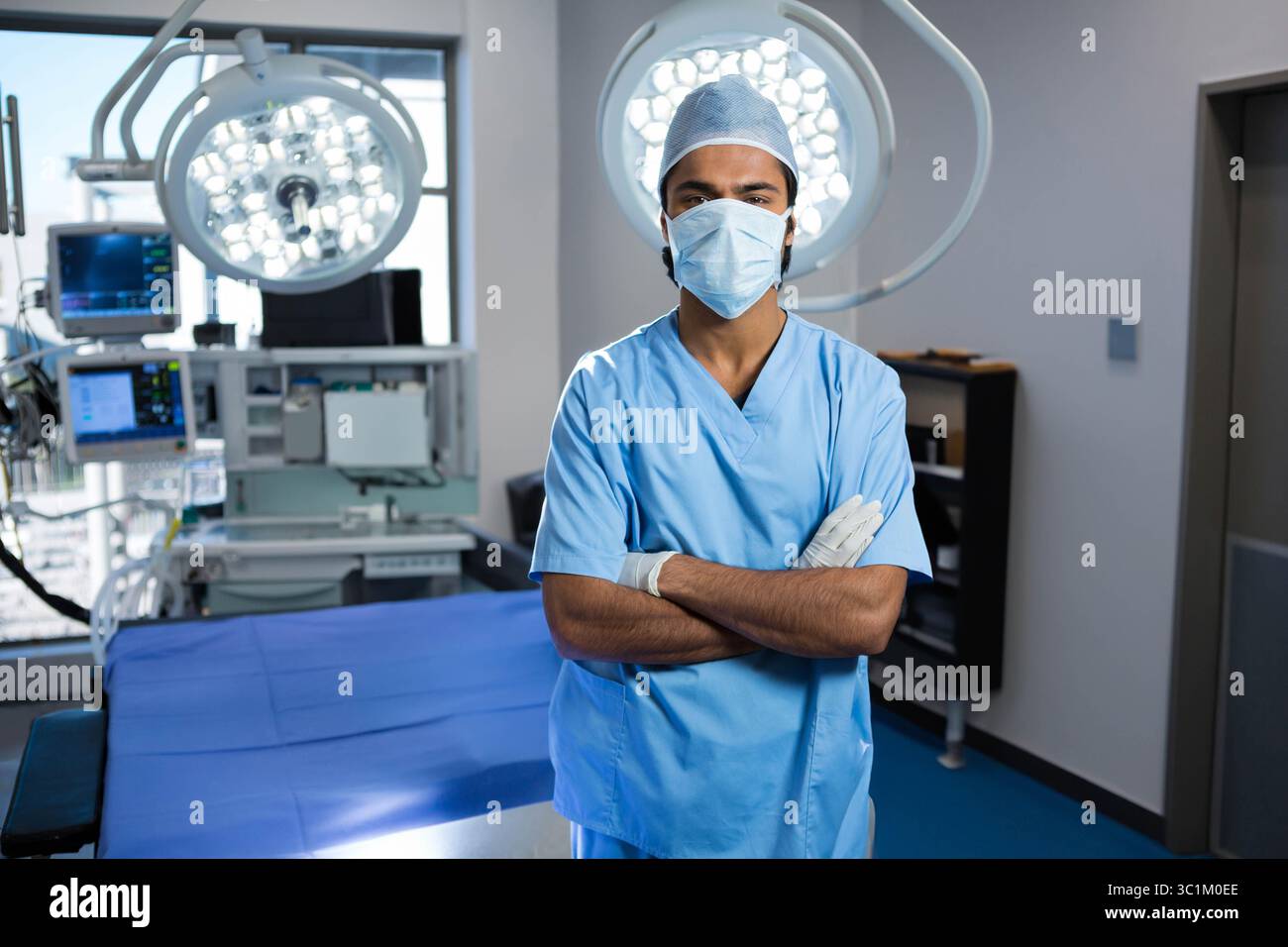 Salle d'opération avec lumières LED éclairant la table drapée de bleu, moniteurs numériques émettant des bips Banque D'Images