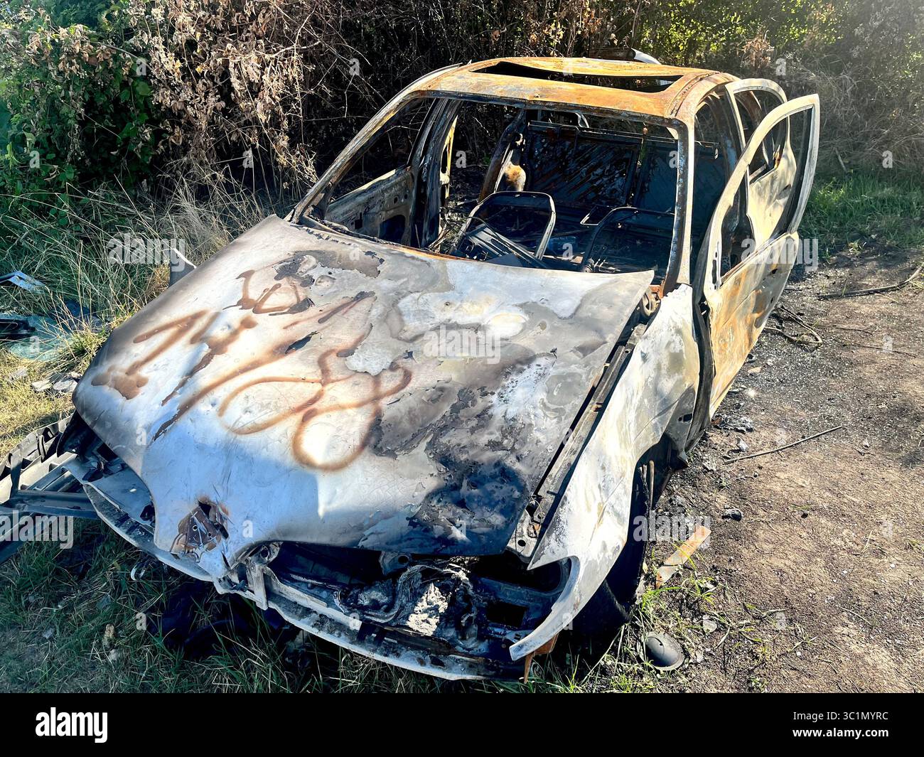 Voiture brûlée Wreck voiture abandonnée, lourdement endommagée et méconnaissable après un incendie, modèle et faire non identifié - Image de stock capturée avec un smartphone