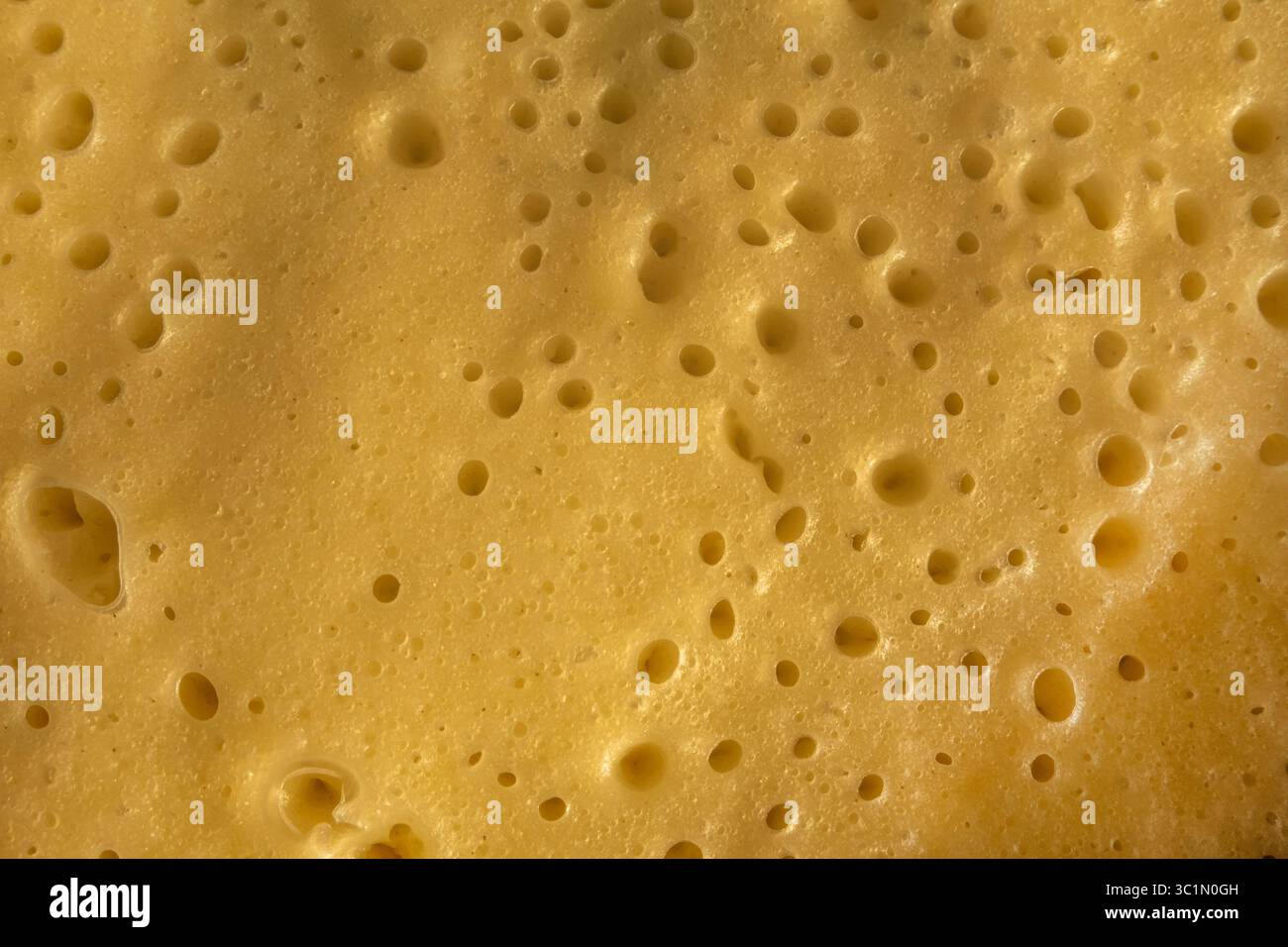 Surface de pâte à crêpes frite avec des trous minuscules. Fond jaune de pâte omelette cuite au four. Pâte à crêpes fraîche avec des taches trop cuites. Banque D'Images