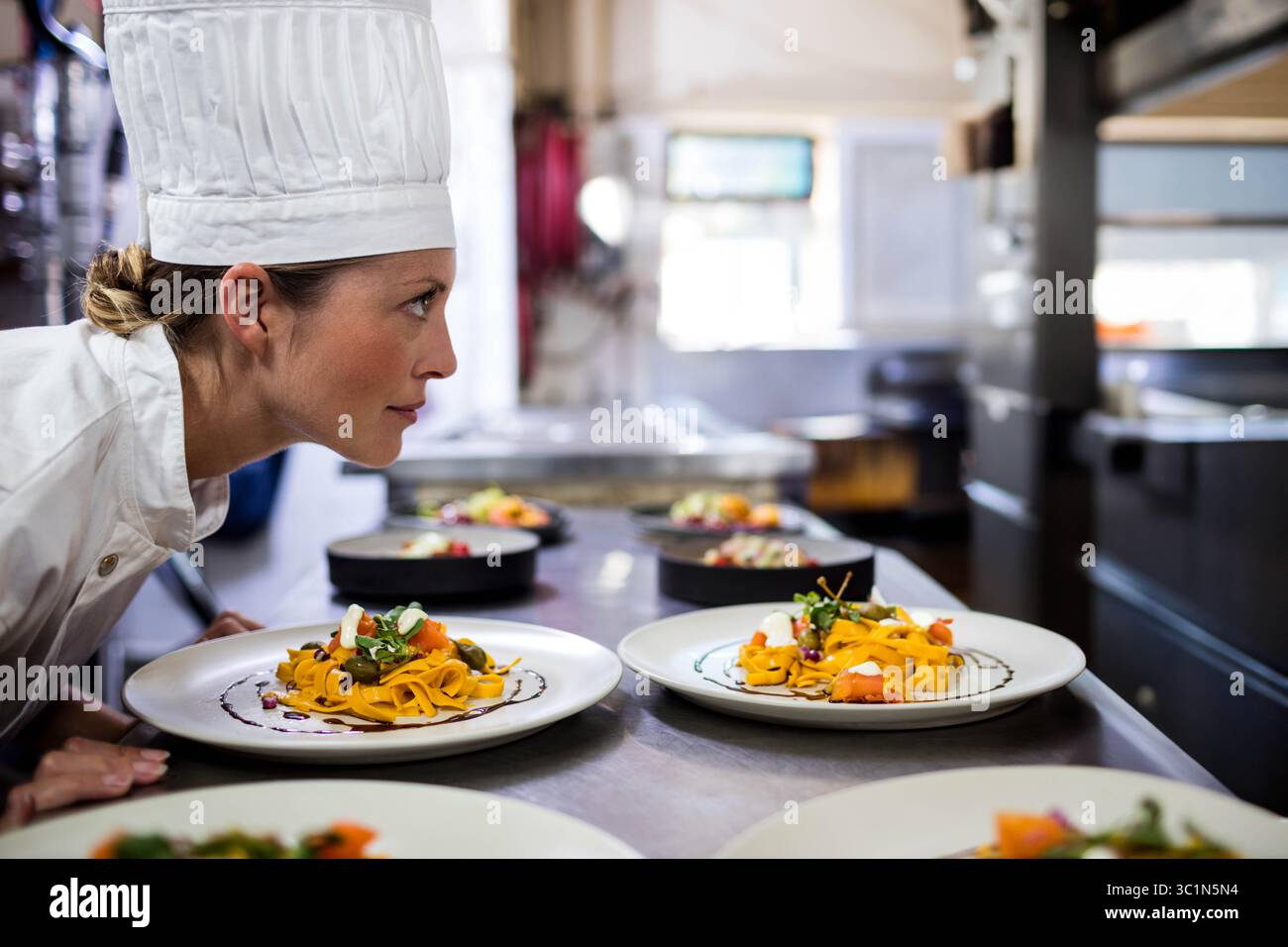 Plats de pâtes de ruban assis sur le comptoir en acier inoxydable près de la fenêtre dans la cuisine occupée Banque D'Images