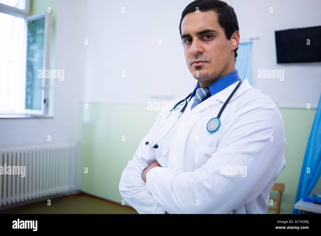 Médecin de sexe masculin debout dans la salle de consultation portant une blouse de laboratoire, une cravate rayée, un stéthoscope, un espace de copie Banque D'Images
