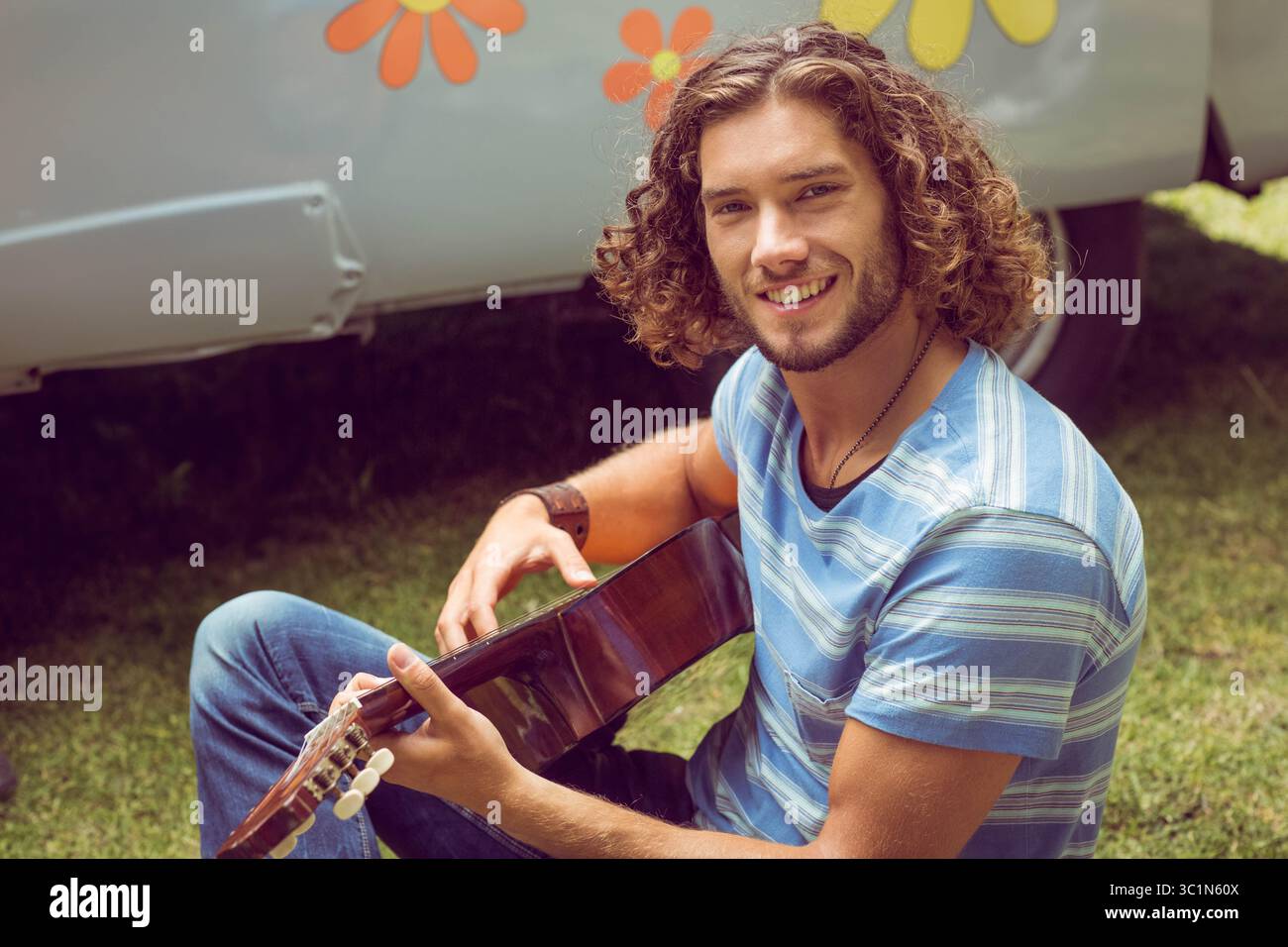guitare acoustique repose sur l'herbe verte devant le camping-car rétro, avec des graphiques de fleurs Banque D'Images