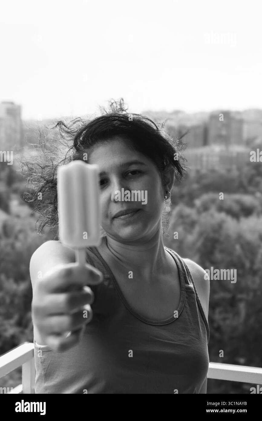 Une femme tenant un bâton de popsicle. Elle porte un débardeur noir Banque D'Images
