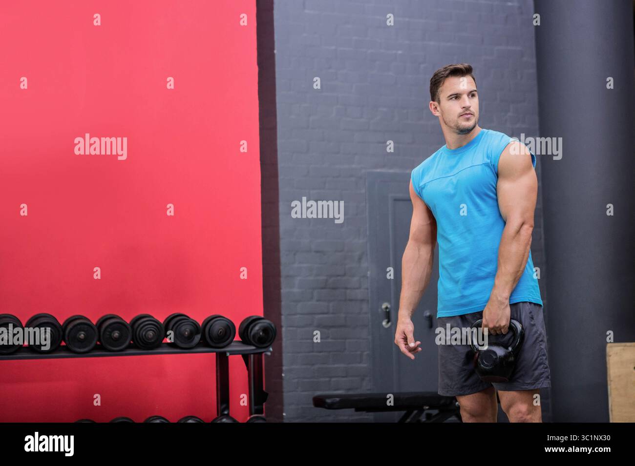 Kettlebell de levage masculin, entraînement dans la salle de gym avec porte-haltères, banc, boîte plyométrique, espace copie Banque D'Images