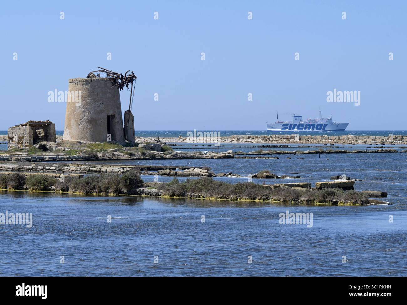 ITALIE, Sicile, Trapani, champs salins pour la production de sel marin, vieux moulin à vent et ferry Siremar / ITALIEN, Sizilien, Trapani, Salinen für Meersalz Herstellung am Stadtrand, Alte Windmühle und Siremar Fährschiff Banque D'Images