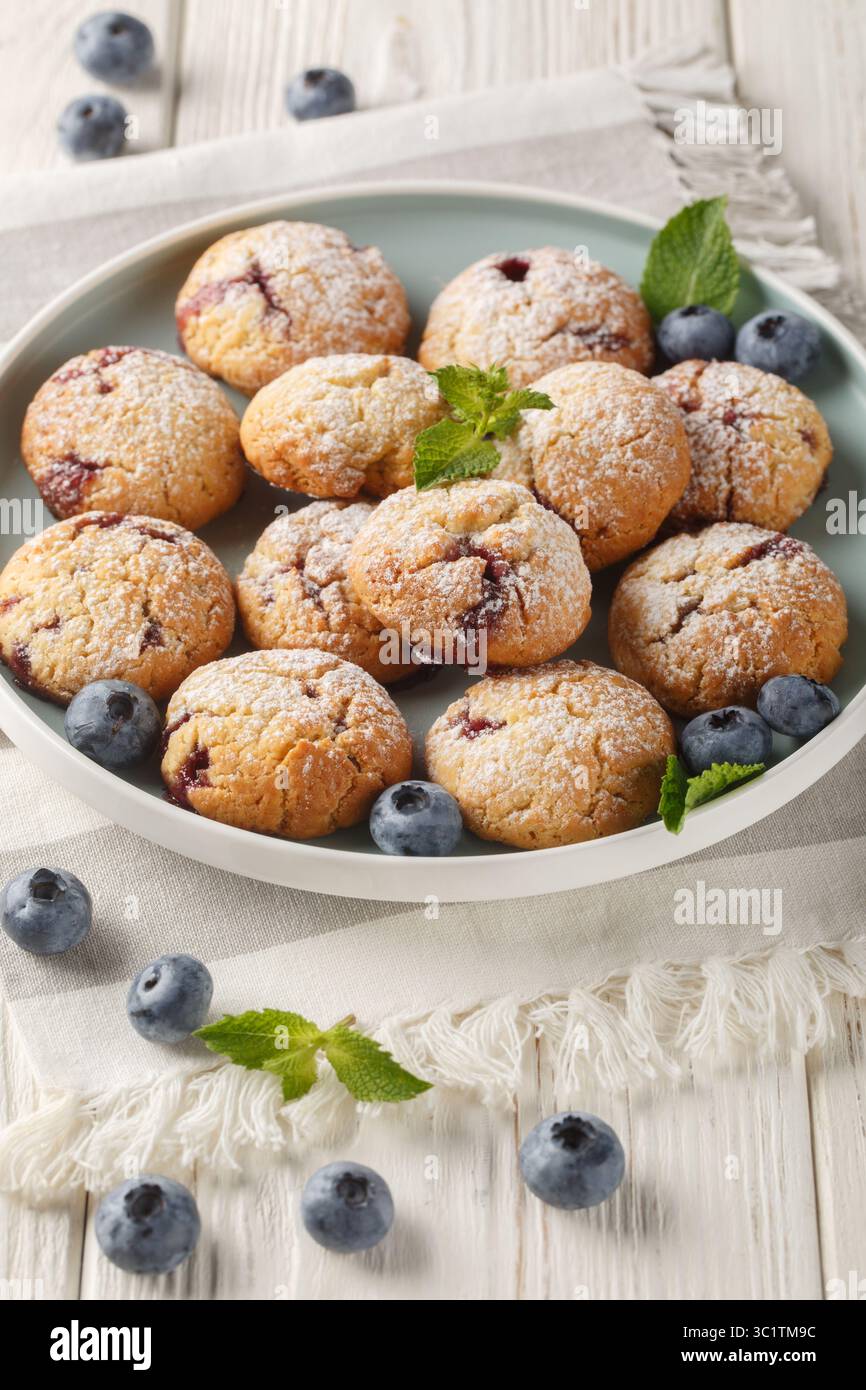 Biscuits avec remplissage de myrtille saupoudrés de sucre en poudre gros plan dans le bol sur la table. Vertical Banque D'Images
