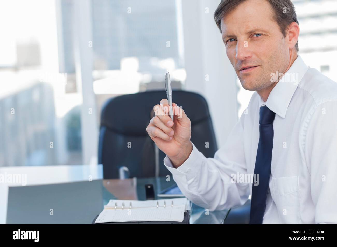Homme d'affaires tenant le stylo au bureau avec le classeur et la tablette et regardant vers la caméra, l'espace de copie Banque D'Images