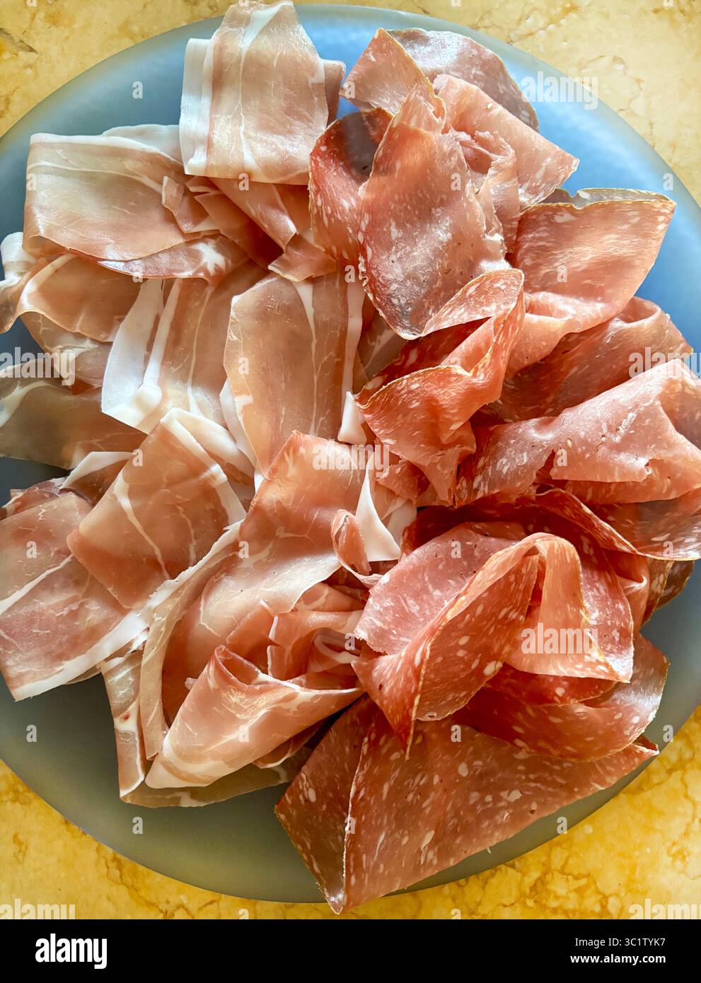 Coupes de savoureux prosciutto crudo italien typique et salami appelé finocchiona dans une plaque bleue. Salami traditionnel de la cuisine italienne. Directement au-dessus. Banque D'Images