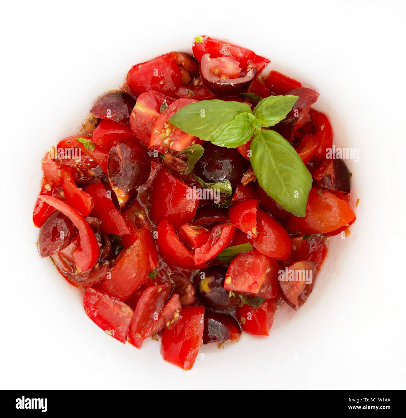Tomates hachées avec huile d'olive, origan et basilic sur fond blanc. Ingrédient pour bruschetta. Cuisine italienne estivale. Nourriture saine et végétarienne. Banque D'Images