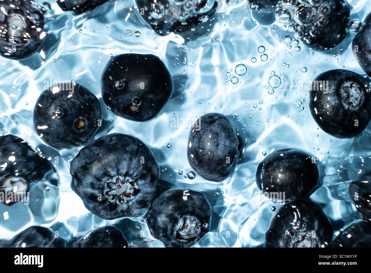 Fond de baies de bleuets entiers frais dans l'eau, éclaboussure d'eau, vue de dessus. Banque D'Images